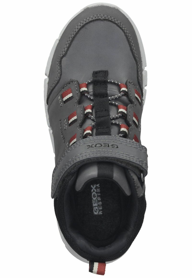 Szare dziecięce sneakersy z czerwonymi, białymi i czarnymi akcentami, z zapięciem na elastyczny pasek i rzep, oraz teksturowaną białą podeszwą.