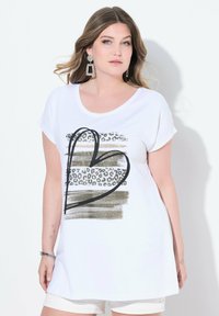 Vit kortärmad t-shirt med en svart hjärtgrafik, guld- och leopardmönstrade detaljer, samt en avslappnad passform. Mjuk bomullsmaterial.