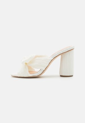 Hvide hæle mules med en plisseret tekstur, åben tå og en knyttet design på overdelen. Chunky, rillede blokhæle for stabilitet.