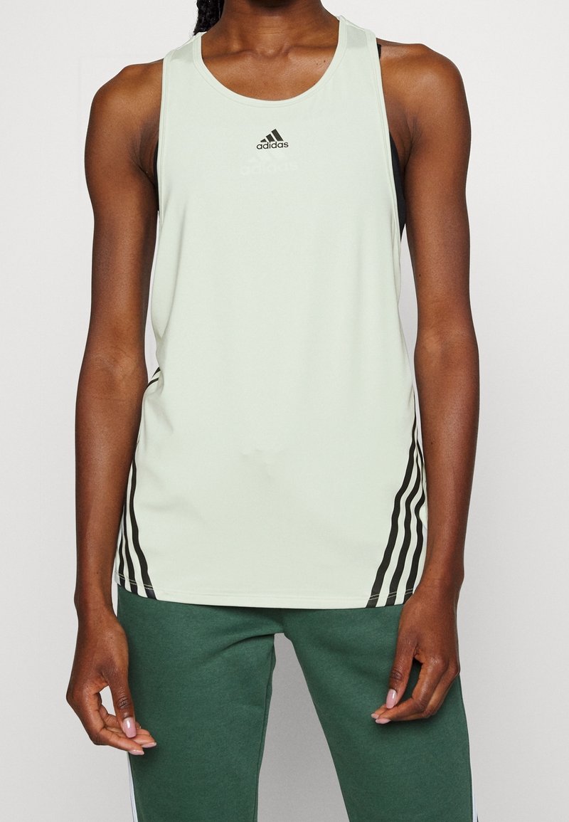 Débardeur athlétique sans manches de couleur vert clair, arborant un logo Adidas noir et trois bandes noires sur les côtés. Confectionné en matériau respirant.