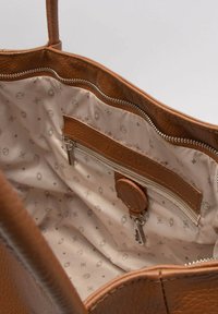 Borsa a spalla in pelle marrone con esterno texturizzato. L'interno presenta una fodera beige con motivi geometrici, una tasca con zip e una chiusura a scatto.
