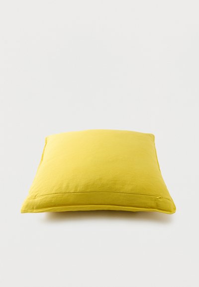 Coussin carré jaune vif avec un design simple sur un fond blanc uni.