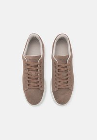 Brown suede sneakers with round toe, white rubber sole, and tonal laces. Features textured body and branded interior.
