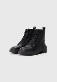 Botas de tobillo de cuero negro con un acabado texturizado, cordones en la parte delantera y cierre de cremallera. Presentan una suela gruesa y lengüetas para facilitar el calzado.