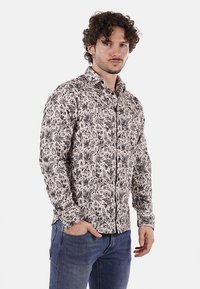 Camicia a maniche lunghe con un motivo floreale bianco e nero, colletto classico, chiusura con bottoni e una vestibilità slim.