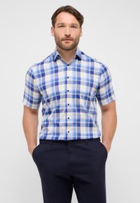 Camicia a maniche corte con un motivo a quadri blu, giallo e bianco. Presenta un colletto con bottoni e bottoni neri. Realizzata in un tessuto leggero.