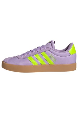 Matala Adidas-tennari vaalean violetilla värillä, neonkeltaisilla raidoilla ja kantalenkillä, ruskealla kumipohjalla, sivukuva.