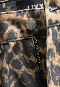 Leopard print fabric, featuring beige and black tones. Metal button accent and visible zipper along the seam. Textured surface.
