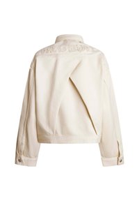 Chaqueta de mezclilla color crema con un diseño corto, que presenta un pliegue único en la parte trasera y el texto bordado "RED BULL" en la parte del trapecio.