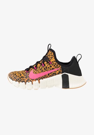 Chaussure de running avec dessus imprimé léopard, talon noir, swoosh Nike rose, lacets noirs et semelle blanche épaisse avec design segmenté.