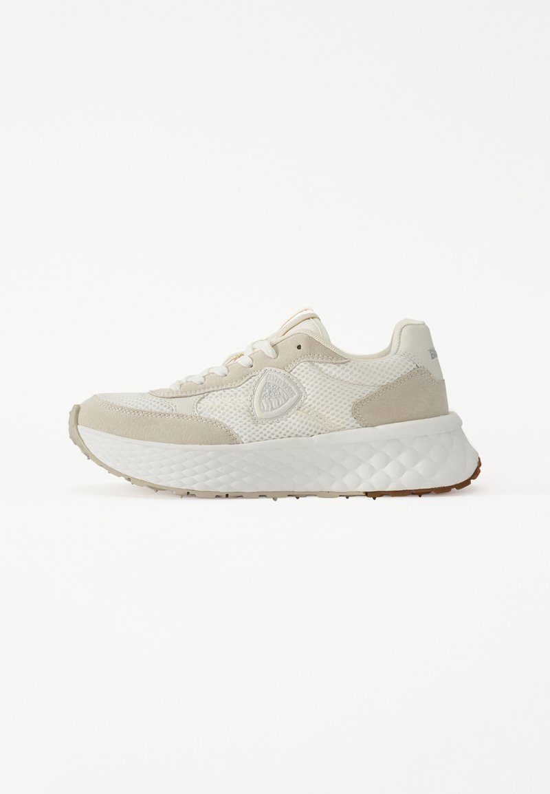 Beige sneaker with mesh and suede materials, textured sole, rounded shape, and a prominent logo detail on the side.