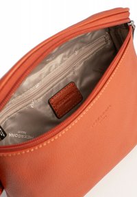 Borsa in pelle arancione con una texture liscia, dotata di una chiusura zip, una tasca interna e un piccolo'etichetta in pelle con logo all'interno.