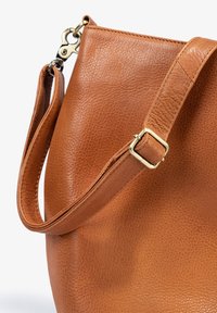 Brown leather handbag with a textured finish. Features a wide strap with a gold-colored buckle and a lobster clasp for attachment.