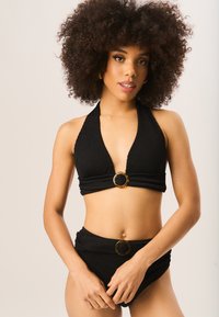 Black bikini set featuring a textured halter top with a deep V-neck and a circular tortoiseshell accent, paired with high-waisted bottoms.
