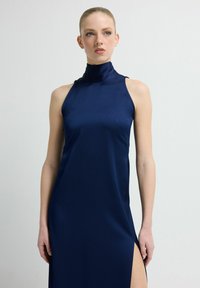 Granatowa sukienka z satyny z wysokim dekoltem, bez rękawów i z rozcięciem po boku, charakteryzująca się gładką fakturą i dopasowanym krojem.