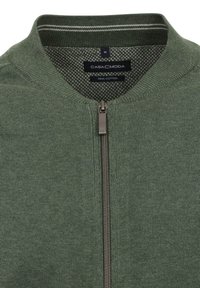 Grüne Zip-Jacke aus Baumwolle. Verfügt über einen gerippten Kragen und subtile Streifenakzente am Hals. Glatte Textur und taillierte Passform.