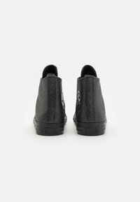 Černé vysoké tenisky s třpytivým povrchem, gumovými podrážkami a svým kulatým logem značky na boku. Hladký povrch a elegantní design.
