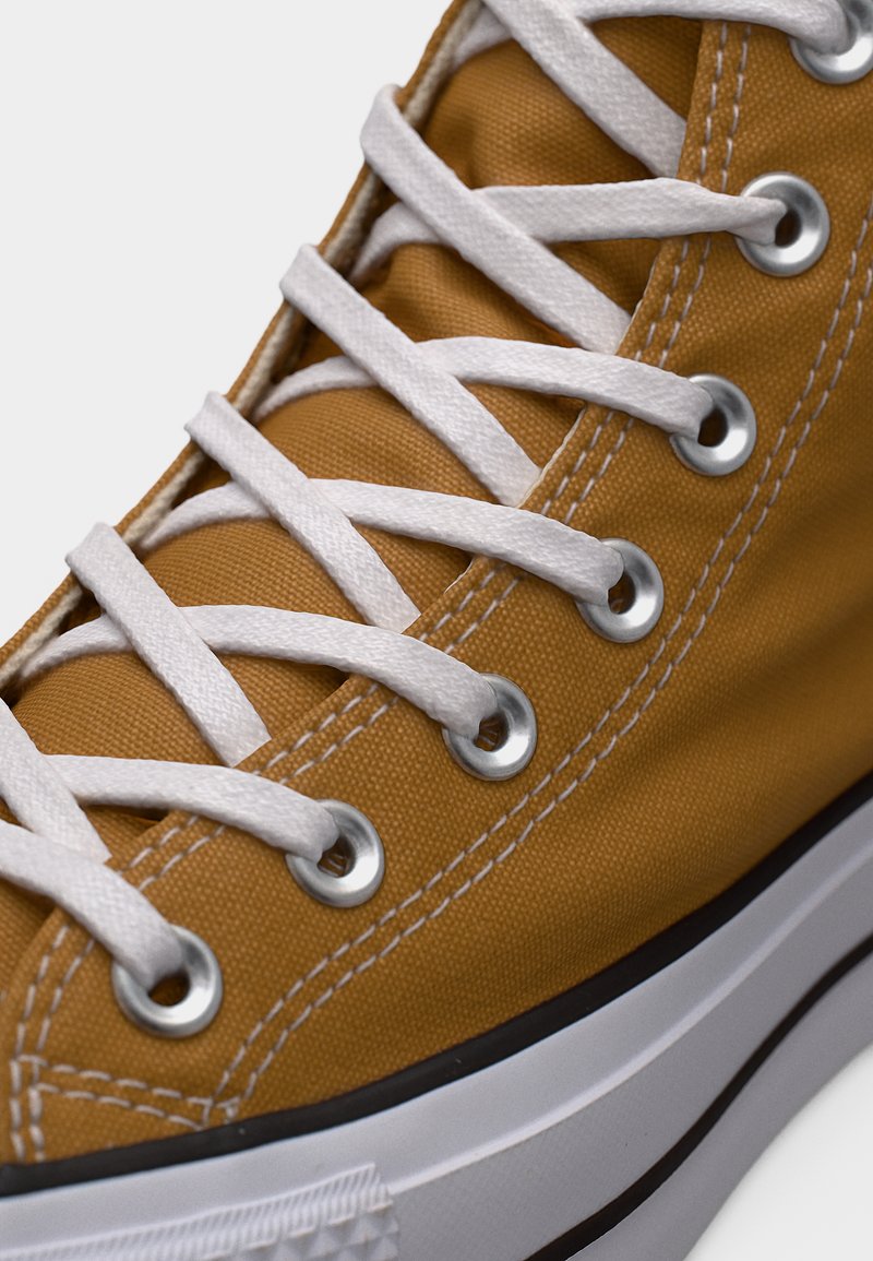 Sneaker in tela gialla con lacci bianchi, occhielli argentati e suola in gomma nera. Presenta dettagli cuciti e una finitura testurizzata.