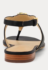 Μαύρες δερμάτινες σαγιονάρες με καφέ εσωτερικό, μικρή χρυσή λεπτομέρεια και καφέ σωρευμένη σόλα. Σχεδίαση ανοιχτής πλάτης με ρυθμιζόμενο λουρί αστραγάλου.