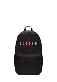 Mochila negra con una textura de tela suave, que presenta un prominente logo "JORDAN" en rojo y blanco con una silueta arriba. Incluye un bolsillo frontal con cremallera.