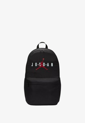 Mochila negra con una textura de tela suave, que presenta un prominente logo "JORDAN" en rojo y blanco con una silueta arriba. Incluye un bolsillo frontal con cremallera.