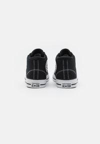Czarne sneakersy wysokie z płótna z białymi gumowymi podeszwami, kontrastowym przeszyciem i ikoniczną łatą z logo po zewnętrznych stronach.