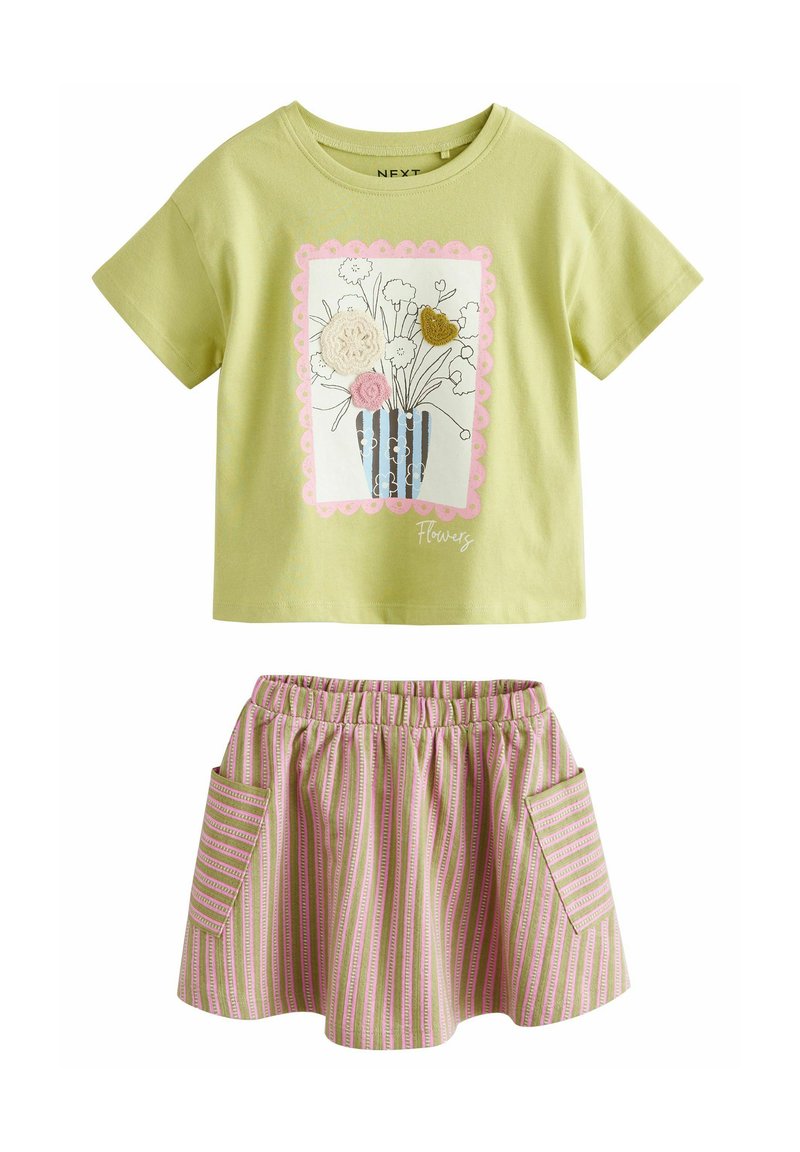 T-shirt verde in cotone con grafica floreale e bordo scallopato rosa. Gonna a righe rosa e verde con due tasche laterali e vita elasticizzata.
