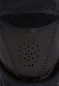 Mascherina nera con un morbido rivestimento interno. Presenta numerosi piccoli fori di ventilazione e un tessuto esterno liscio e elasticizzato.