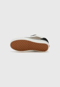 Semelle de basket noire et grise, dotée d'un dessous en caoutchouc gomme texturé et d'un entresemelle blanche. Design simple avec un branding minimal et des coutures épurées.