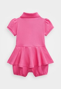 Růžový krátký overal s krátkým rukávem vyrobený z texturované tkaniny, se zapínáním na polo límeček a volánkovým detailem v pase.