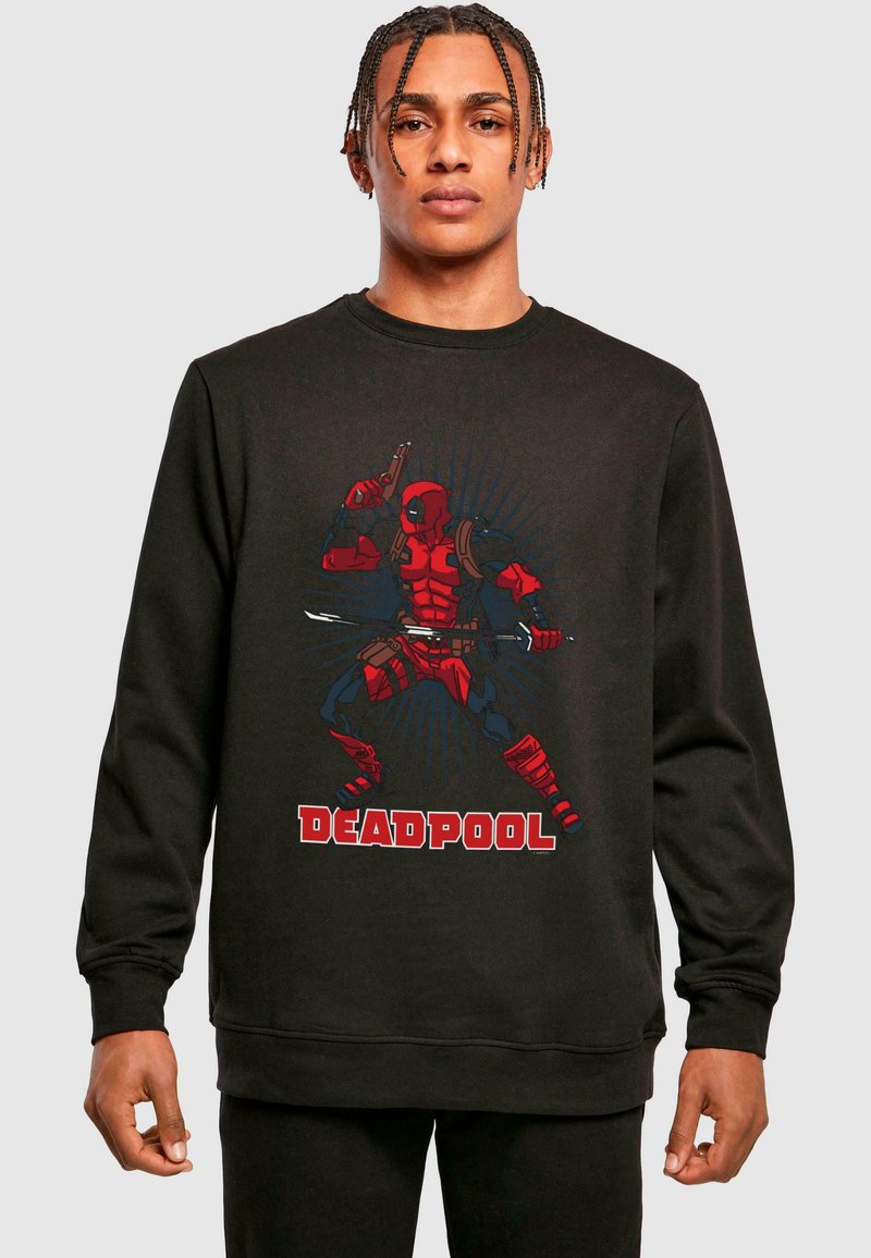 Melna džemperis ar sarkano Deadpool grafiku komiksu stilā, akcentējot izteiksmīgas līnijas un dinamisku pozu.
