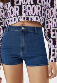 Denim shorts with a high waist design, made from dark blue fabric. Features subtle fading, gold-colored hardware, and stitched hem details.