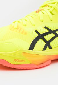 Zapatilla deportiva de un brillante color amarillo con un upper texturizado, acentos negros y una suela vibrante naranja con la marca "FFBlast+".