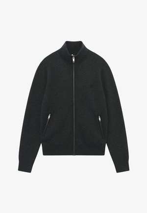 Sweat à zip gris foncé avec un col montant, fabriqué dans un tissu texturé, doté de deux poches zippées sur les côtés et d'un logo discret sur la poitrine.