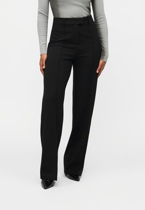 Černé kalhoty na míru s vysokým pasem, rovnými nohavicemi a jemnými předními záhyby. Látka má hladkou texturu a je lehká.