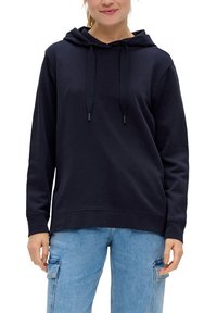 Marineblauwe hoodie met trekkoorden, zachte stof, kangoeroezak en geribde zoom. G draagt het met lichte denim jeans.