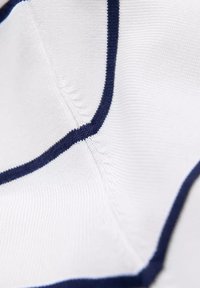 Tessuto bianco con una fine trama a righe, caratterizzato da cuciture e dettagli blu scuro alle cuciture, che mettono in risalto un design su misura.