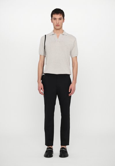 Polo tričko s krátkym rukávom v svetlosivej pletenine, so zapínaním na dva gombíky, skombinované s čiernymi slim-fit nohavicami a čiernymi mokasínami.