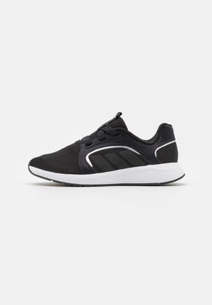 Czarne sportowe buty z siateczkową cholewką, sznurowaniem i trzema paskami. Posiadają białą podeszwę środkową i czarną podeszwę zewnętrzną dla lepszej przyczepności.