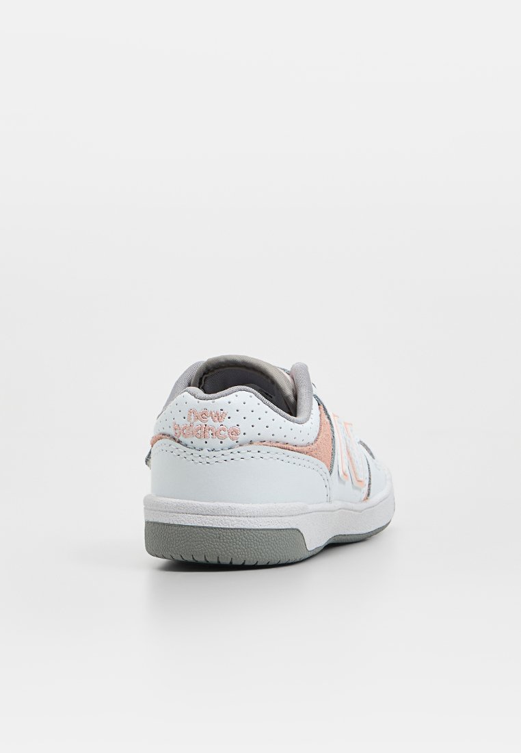 Sneaker bianca con suola grigia, caratterizzata da accenti rosa e dettagli perforati. Ha una morbida fodera in tessuto e un tacco piatto.