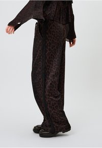 Lupatu raksta platas kājas bikses melnbaltā satīna audumā, ar teksturētu apdari un sānu akcentiem.