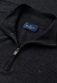 Donkergrijze zip-up sweater met een staande kraag, gestructureerde stof en een klein geborduurd logo. Etiket zichtbaar met "HACKETT LONDON."