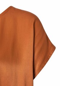 Krótki rękaw w intensywnym, spaloną pomarańczową kolorze. Gładka faktura z delikatnym połyskiem, z luźnym krojem i minimalnymi detalami szwów.