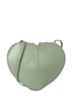 Sac bandoulière en cuir vert en forme de cœur avec fermeture éclair dorée et sangle fine, isolé sur fond blanc.