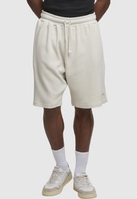Kremfarvede shorts i vaffelstrik med elastisk talje, justerbar snøre og sidelommer. Kombineret med hvide sneakers og mellemlange sokker.