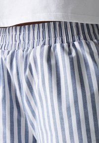 Blue and white striped pajama shorts with an elastic waistband, featuring smooth cotton fabric and well-defined vertical stripes.