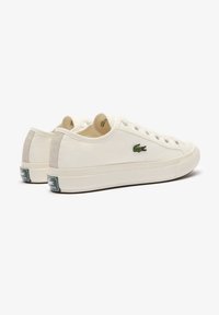 Zapatillas de lona crema con detalles en ante gris, cordones blancos, puntera redonda, logo bordado verde y una gruesa suela de goma blanca.