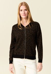 Brun zip-up cardigan med svart leopardmönster, ribbad mudd och nederkant, tillverkad av mjukt material, med ståkrage.
