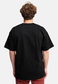 Sort bomulds T-shirt med korte ærmer, en afslappet pasform og rund halsudskæring, der har minimale sømme og en glat overflade.