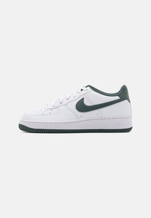 White low-top sneaker with dark green Nike swoosh, laces, collar, and sole, side view on a light gray background.